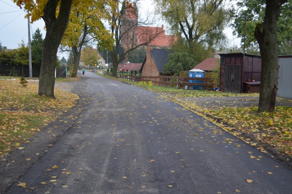 Nowa nawierzchnia bitumiczna na drodze w Lalkach. W tle kościół